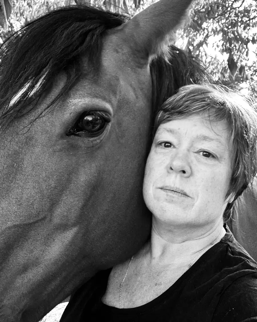Anne Boutillon, blottie contre la tête d'un cheval bai, praticienne en shiatsu équin en Tarn-et-Garonne
